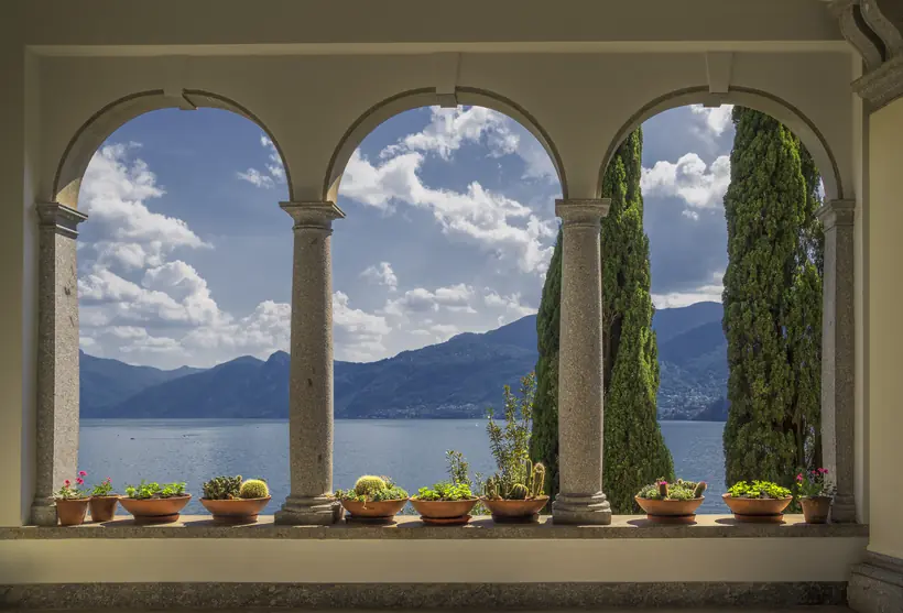 A stone arcade opening onto a lake and mountains beyond.