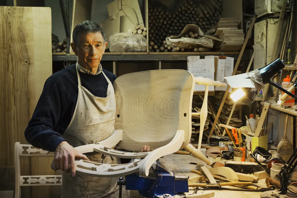 A chairmaker steadying a curved seat frame at the workbench.