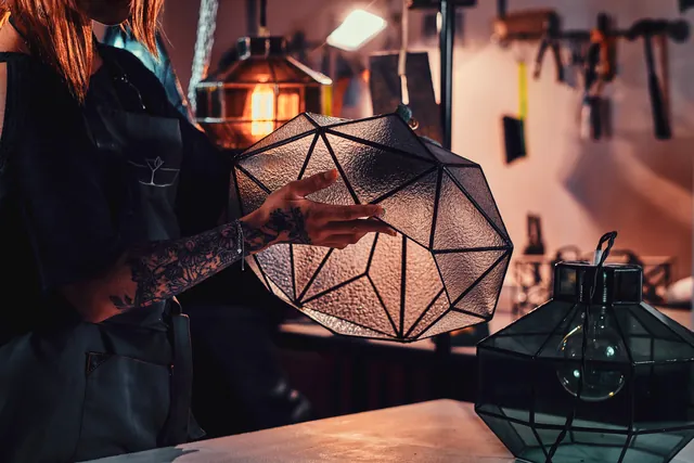 A faceted glass pendant being assembled under a work lamp.
