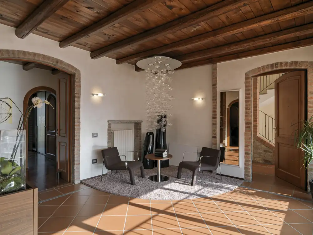 A beamed interior with tiled floor and arched openings.