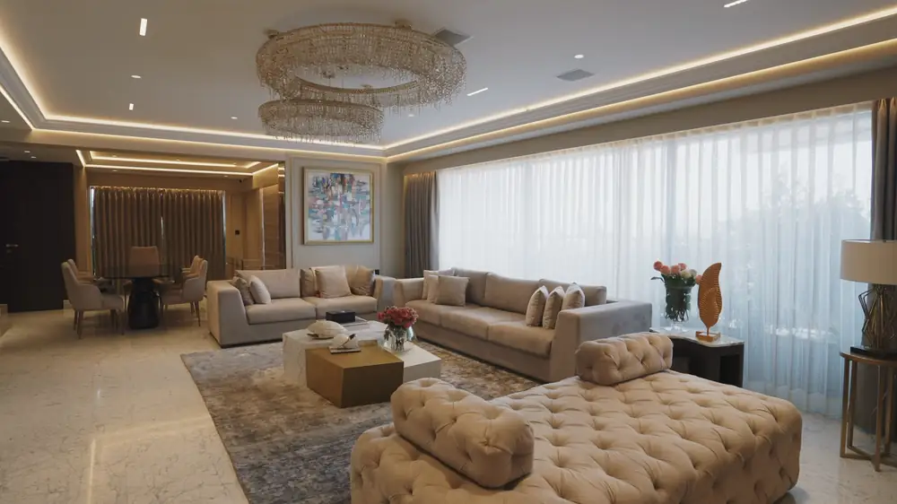 A reception room with layered seating, sheer curtains and a tiered chandelier.