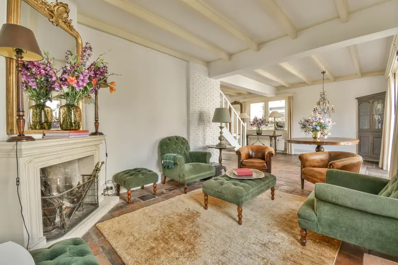 A reception room with a fireplace, layered seating and tall windows.