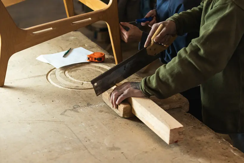 Hands guiding a length of timber across a workbench.