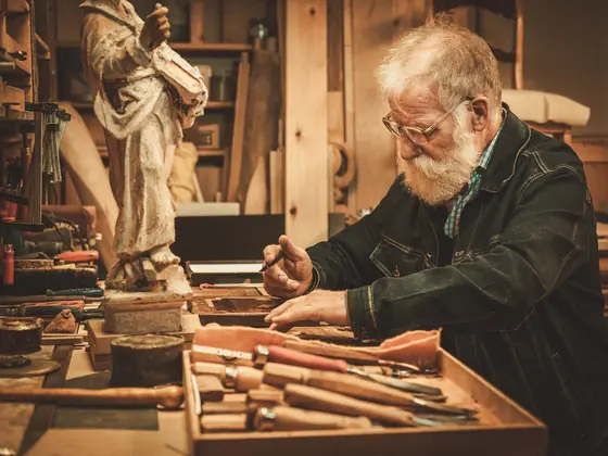 A restorer working on an antique decorative element at his bench.