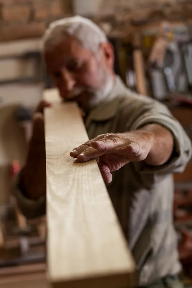 A woodworker sighting along a board to check it for straightness.